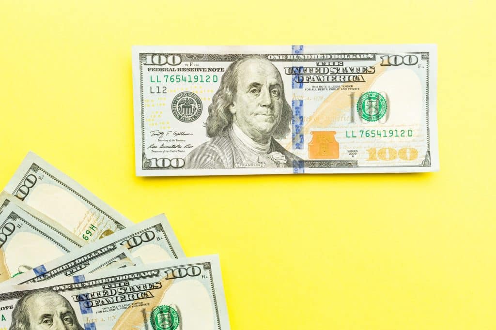 One hundred dollars bill lying on yellow background