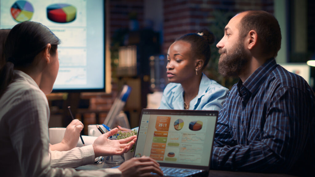 Coworkers sit at a table and discuss statistics